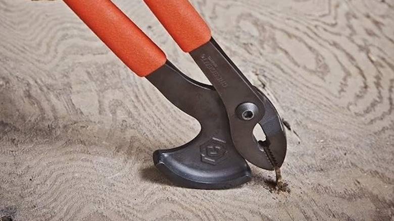 Nail pullers removing a screw from a piece of wood.