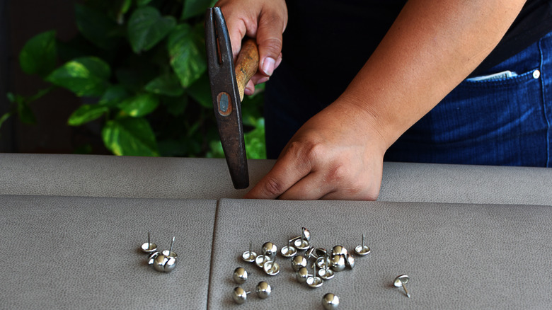 Hands putting upholstery tacks into furniture