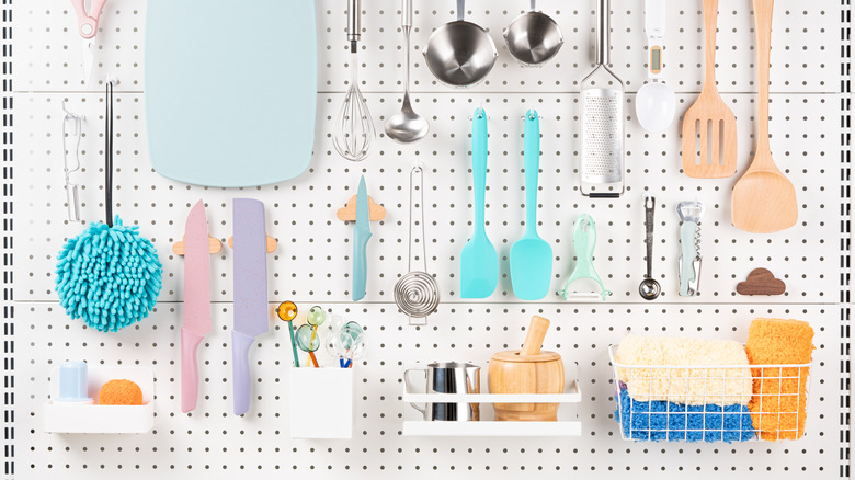 Pegboard holding kitchen utensils and cutting boards