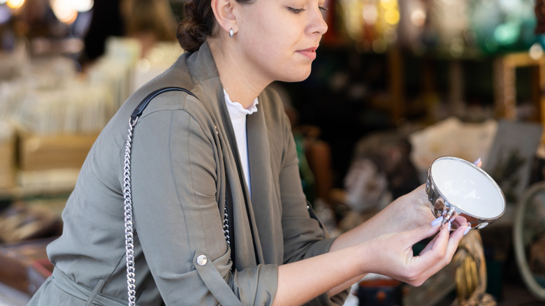 A woman looking at a teacup at a flea market