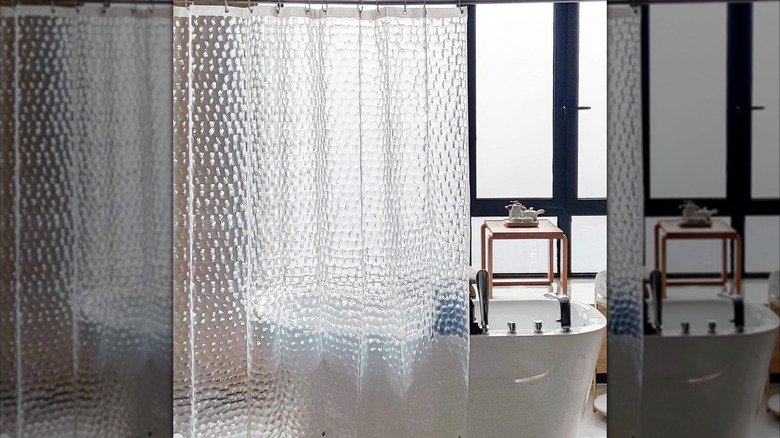 A clear textured shower curtain hung up beside a freestanding tub.