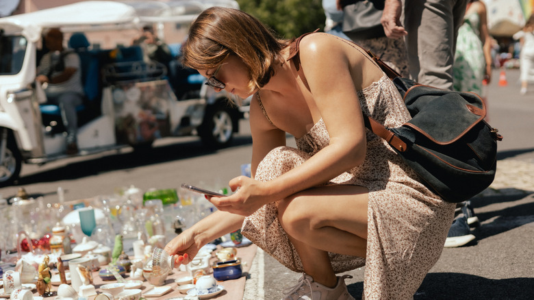 A woman shops for kitchenwares at an outdoor secondhand market.