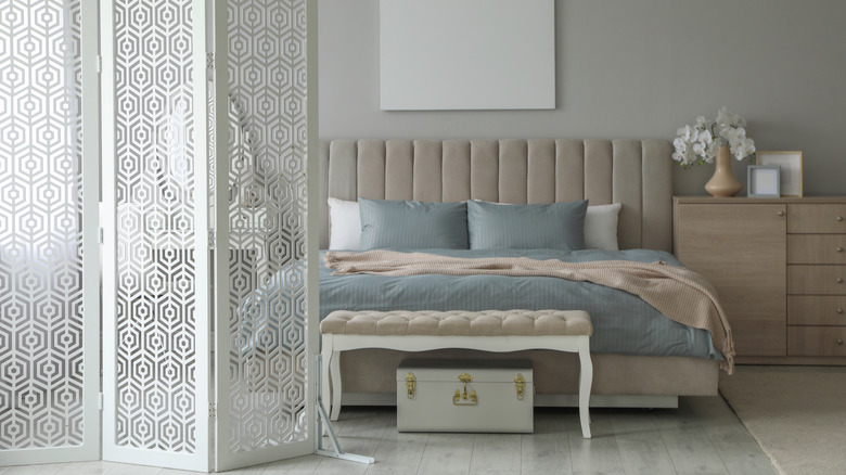 A vintage bedroom with a wood folding screen