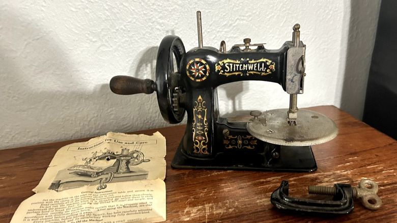 An antique cast iron sewing machine displayed on a table with the original owner's manual