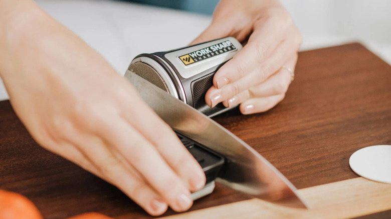 a person using a rolling sharpener to sharpen a knife