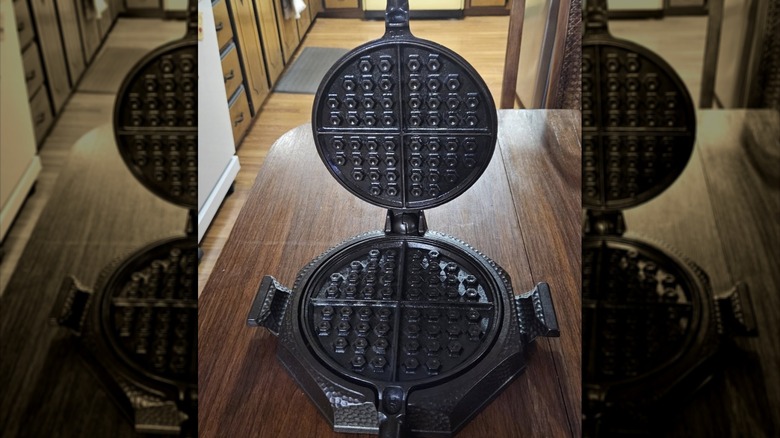 Example of a Griswold hammered waffle iron, open and sitting on a wood table