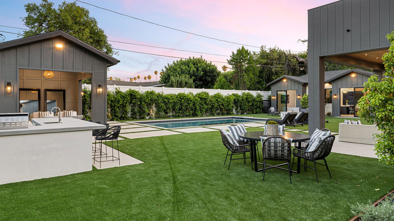 A backyard with a bar, dining area, and small pool at sunset