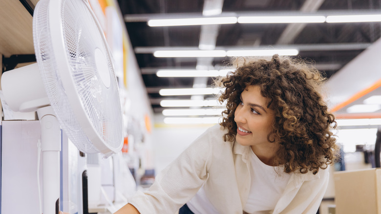 A woman shops for a fan in a store