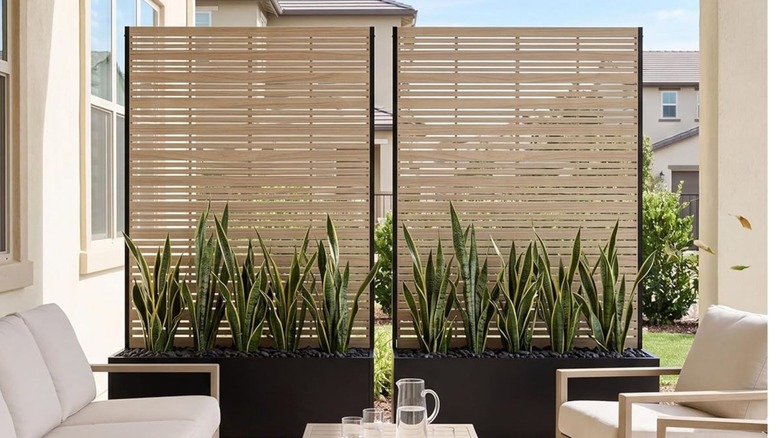 Two side by side screen planters on a stylish patio, with snake plants in the bottom