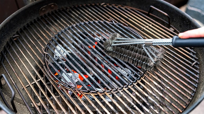 Person cleaning a grill with a wire brush