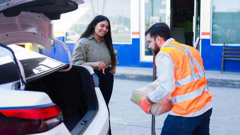 Employee loading bags into a customer's car.