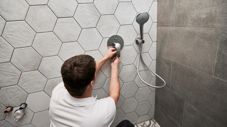 A plumber works on installing a shower faucet set
