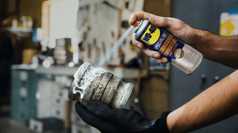 person spraying WD-40 on a metal fitting