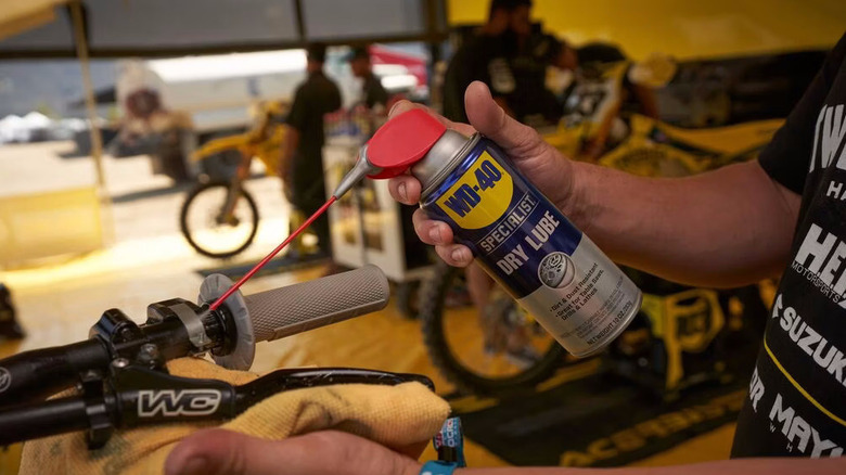 a person spraying WD-40 Specialist Dry Lube on a bike's handle