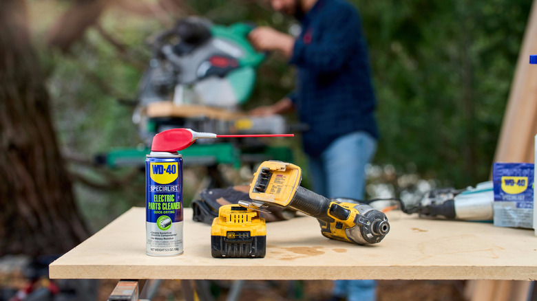 a spray can of WD-40 Specialist Electric Parts Cleaner on a bench next to a drill