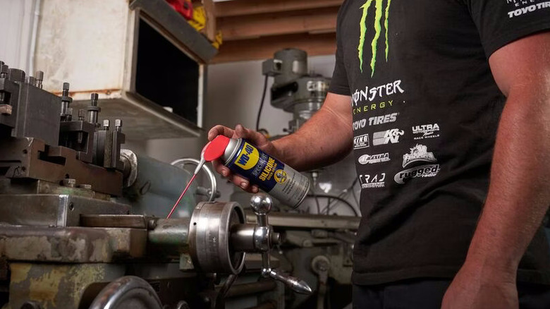 a person applying WD-40 Specialist Silicone to a metalworking lathe