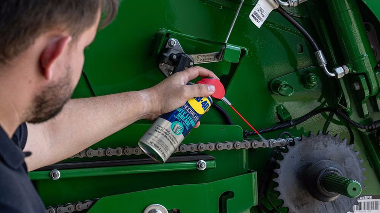a person spraying WD-40 Specialist White Lithium Grease on a chain