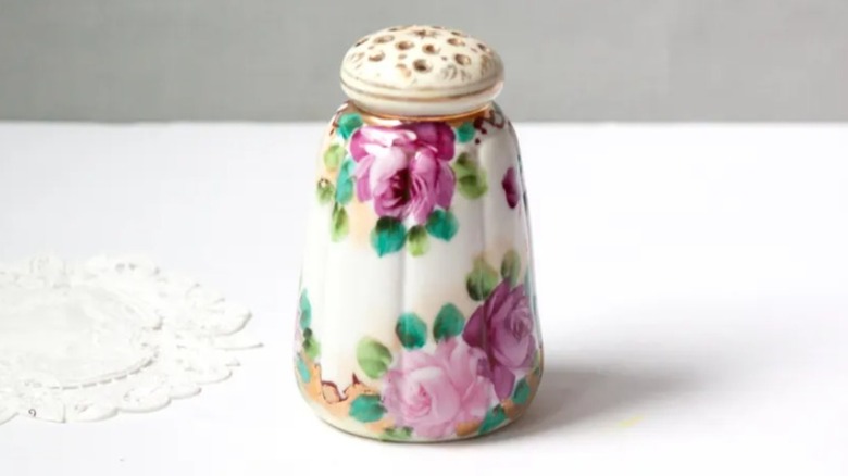 A vintage salt shaker next to a doily