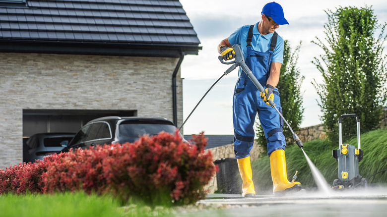 person cleaning driveway with a power washer