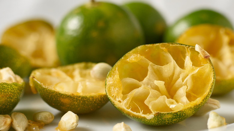 Juiced and old half limes with seeds on a white countertop.