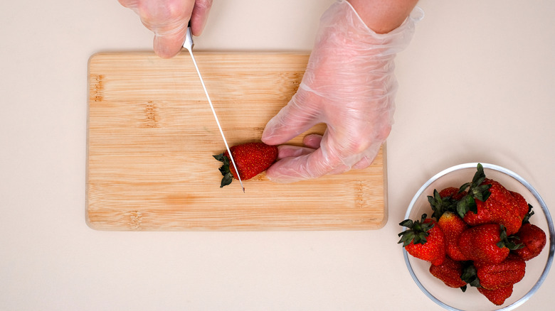person cutting tops off strawberries