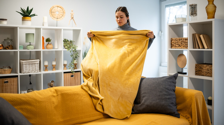 Woman folding a yellow throw blanket