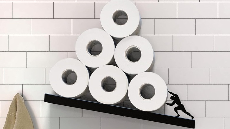 The Artori Floating Toilet Paper Shelf Storage with rolls of toilet paper on the wall in a bathroom.