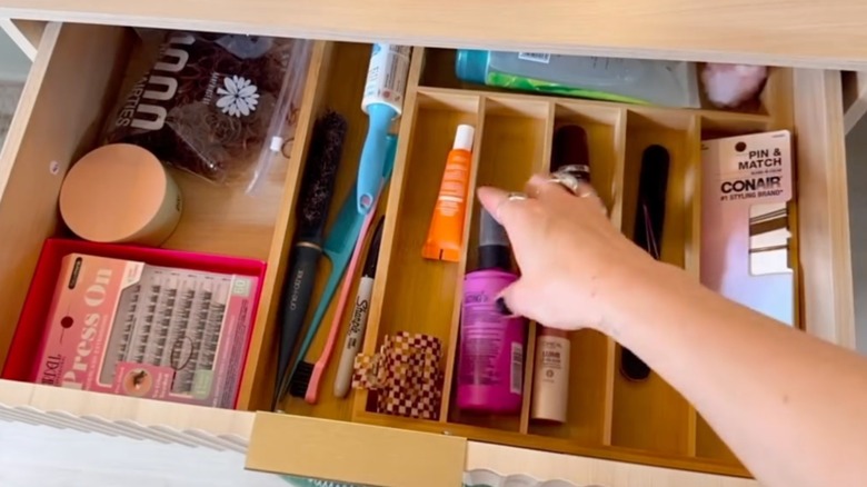 a utensil organizer being used in a drawer to hold makeup