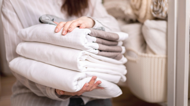 Person holding a stack of towels and linens