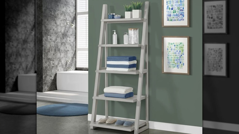 Kellen ladder shelf placed in bathroom with plants, products, towels, and slippers on shelves