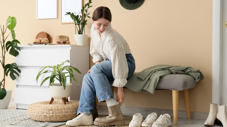 A person sitting in entryway putting on their shoes
