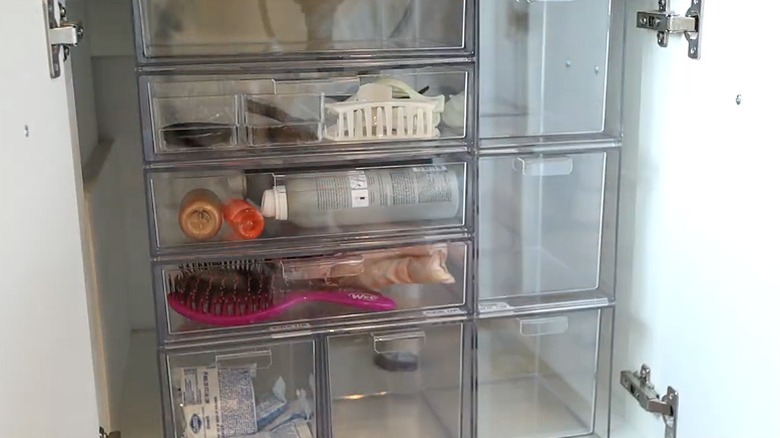 A deep shelf under a bathroom storage cabinet is organized with stackable drawers.