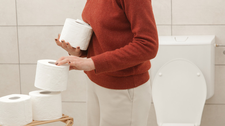 Woman storing toilet paper in a bathroom