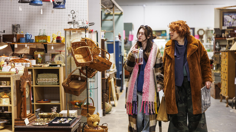 Two women walking through a vintage store filled with baskets and trinkets