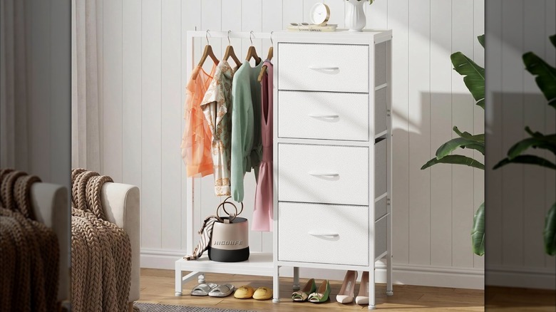 Image of a white dresser and hanging rack unit with clothes on it