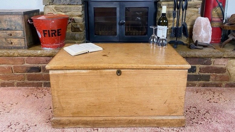 light wood blanket box in front of a fireplace