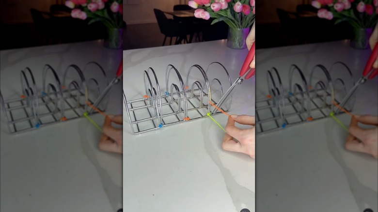 A hand with scissors snipping the ends of zip ties that are connecting napkin holders