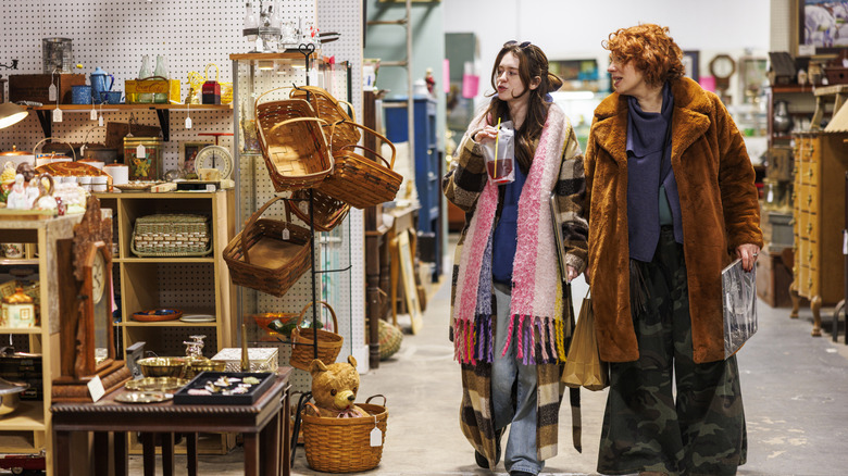 Two women looking at baskets and other items at a thrift shop.