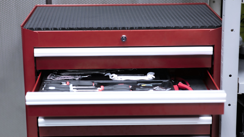A close-up of a red tool cabinet with one drawer open