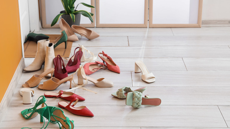 An assortment of shoes scattered on the floor in a hallway
