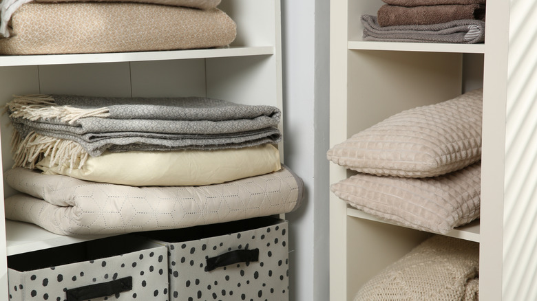 Closet with blankets, throws, and pilllows arranged on shelves