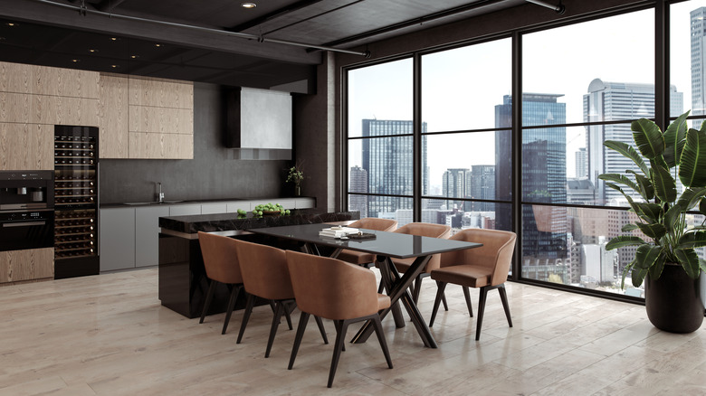 Neutral black and brown kitchen and dining area, with cityscape in the background window.