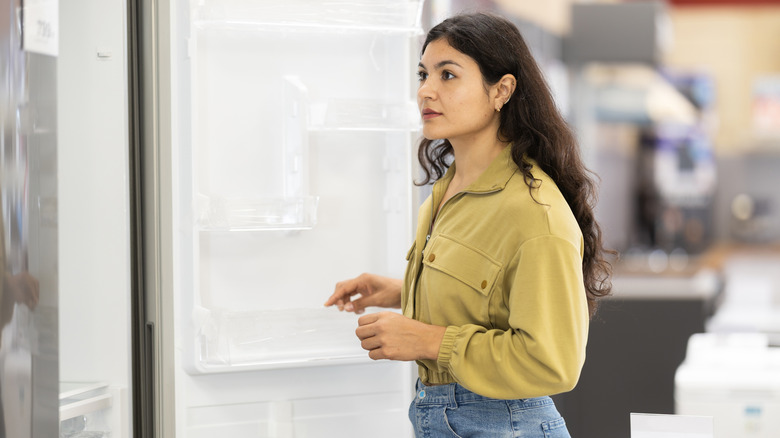 Young woman with dark hair shopping for a new refrigerator in a store