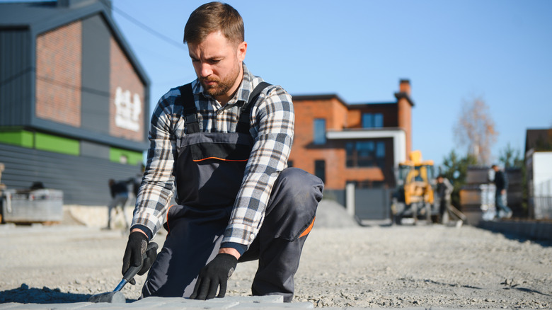 A worker installing pavers in a landscape.