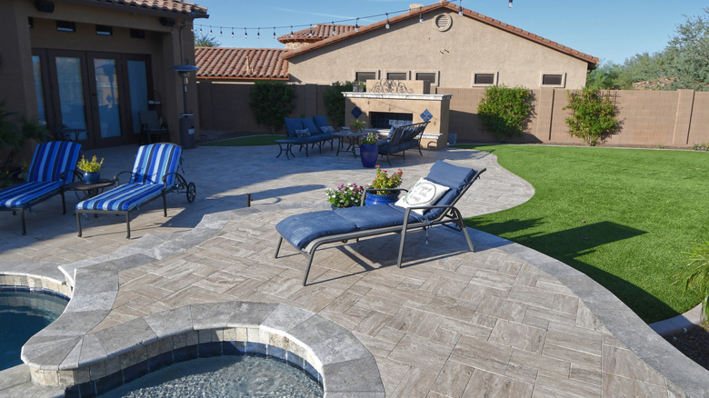 A patio with a pool and travertine pavers.