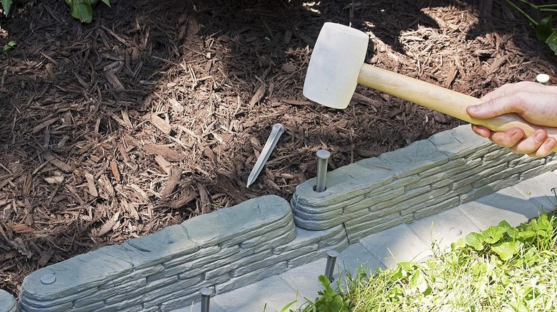Someone hammering Amazon's Emsco Group Natural Stacked Slate Edging together