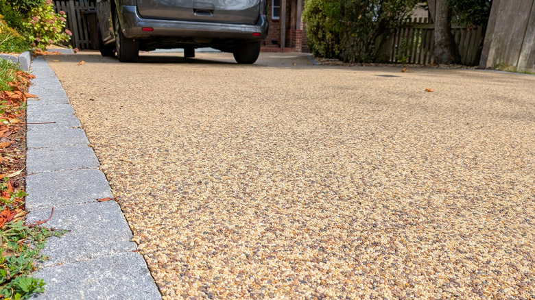 a driveway with block paved edging and parked car in the background