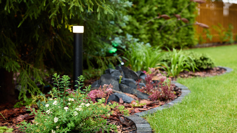 Brick landscape edging keeps a lawn separate from a mulched flower bed and crevice garden