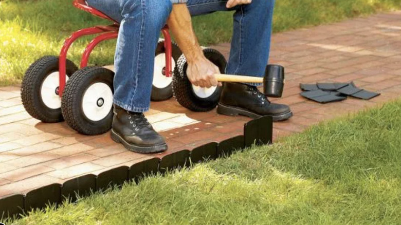Man using a rubber mallet to install pound in edging.