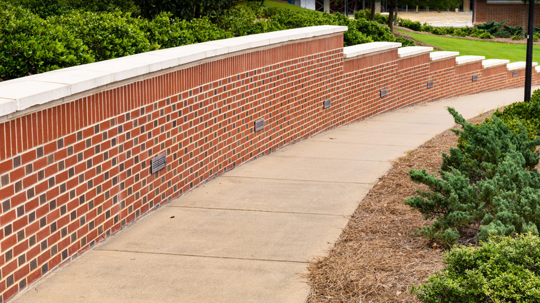 A red brick retaining wall beside a sidewalk
